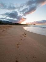 empreintes de pas sur la plage pendant le coucher du soleil photo
