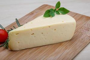 Fromage jaune sur planche de bois et fond de bois photo