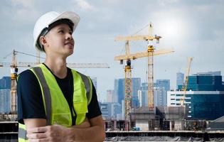 ingénieur civil asiatique ou architecture, ouvrier professionnel portant un chapeau blanc impatient de réussir, jeune homme adulte travaillant sur un chantier de construction, concept de travail réussi. photo