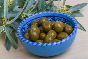 olives vertes dans un bol sur fond de bois photo