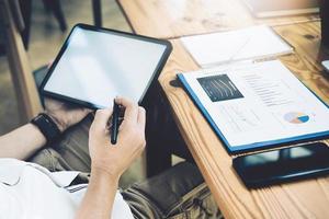 liberté financière, un analyste boursier tenant un stylo pointant vers une tablette analyse le marché boursier pour réaliser un profit pour votre propre portefeuille. photo