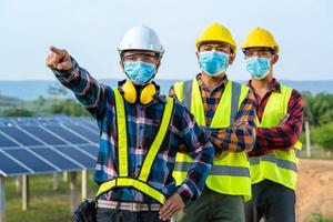 travailleurs masqués à côté du panneau solaire photo