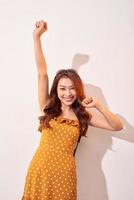 jeune belle femme asiatique dansant heureuse et joyeuse, souriante se déplaçant décontractée sur fond beige photo