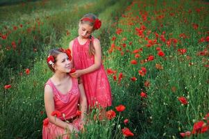 deux filles en robes roses dans un champ de pavot photo