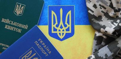 carte d'identité militaire ukrainienne et passeport étranger sur tissu avec texture de camouflage pixélisé. tissu avec motif camouflage dans des formes grises, brunes et vertes avec jeton personnel et passeport de l'armée ukrainienne. photo