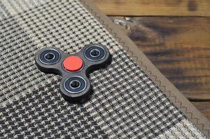 un spinner fait main en bois rare se trouve sur un plaid à carreaux sur une surface de fond en bois marron. jouet anti-stress tendance photo