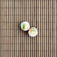 les rouleaux de sushi reposent sur un tapis de couture en paille de bambou. cuisine asiatique traditionnelle. vue de dessus. minimalisme à plat tourné avec espace de copie photo
