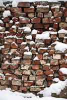 la texture de l'ancien mur de briques, recouvert d'une épaisse couche de neige après une forte chute de neige photo