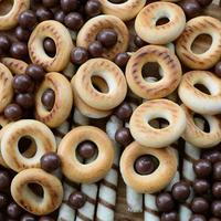 beaucoup de tubules sucrés croustillants, de boules fondantes au chocolat et de bagels jaunes reposent sur une surface en bois. vue rapprochée photo