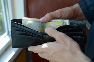 gros plan des mains masculines a ouvert le portefeuille ou le sac à main avec de l'argent ukrainien hryvnia photo