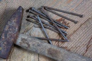 différents outils sur un fond en bois. des clous et un marteau photo