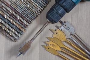 différents outils sur un fond en bois. perceuse, perceuse à bois, foret à béton photo