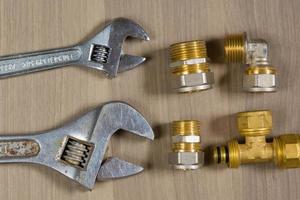 différents outils sur un fond en bois. clé à molette et pièces de plomberie photo