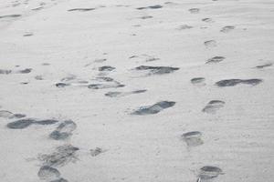 photo de l'apparition de sable noir sur la plage et d'empreintes humaines