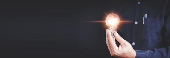 idée innovation et concept d'inspiration. main d'homme tenant une ampoule illuminée, créativité conceptuelle avec des ampoules qui brillent de paillettes. inspiration d'idées pour le développement durable des entreprises. photo