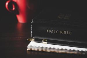 livre de la sainte bible avec du papier pour l'éducation sur fond de bois noir. chrétien catholique avec culte protestant et prière à l'église. concept d'apprentissage de la foi dieu et de la religion, jésus spirituel. photo