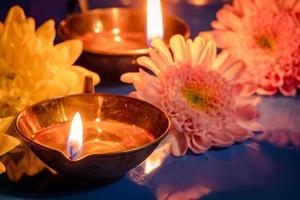 joyeux Diwali. brûler des lampes à huile diya et des fleurs sur fond bleu. fête traditionnelle indienne de la lumière. photo