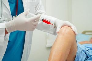 un médecin asiatique injecte du plasma riche en plaquettes d'acide hyaluronique dans le genou d'une femme âgée pour marcher sans douleur. photo