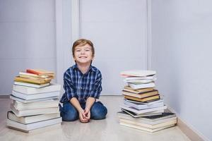 enfant heureux parmi la pile de livres et regardant la caméra. photo