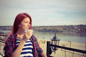 femme réfléchie appréciant une tasse de café à la plage. photo