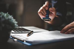 homme tamponnant l'approbation des documents bancaires de financement du travail ou de marketing d'investissement sur le bureau. photo