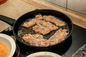 côtelettes de boeuf dans une casserole sur la cuisinière. le processus de préparation des côtelettes de boeuf dans la pâte photo