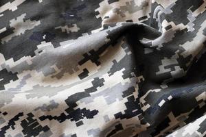 tissu avec une texture de camouflage pixélisé militaire ukrainien. tissu avec motif camouflage en formes de pixels gris, marron et vert. uniforme officiel des soldats ukrainiens photo