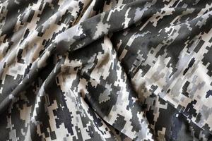 tissu avec une texture de camouflage pixélisé militaire ukrainien. tissu avec motif camouflage en formes de pixels gris, marron et vert. uniforme officiel des soldats ukrainiens photo