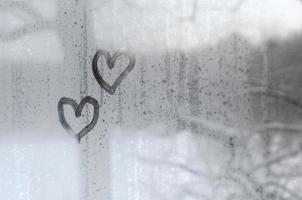 deux coeurs peints sur un verre embué en hiver photo
