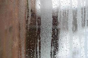 la texture d'un verre embué avec beaucoup de gouttes et de flux de condensation. image de fond photo