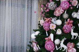 décoration de sapin de noël en gros plan. ampoule de décoration, sapin, jouets et lumières roses de Noël. utiliser pour le fond de célébration de noël et du nouvel an photo