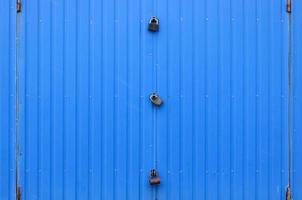 texture d'un mur bleu métallique avec une porte fermée pour trois serrures photo