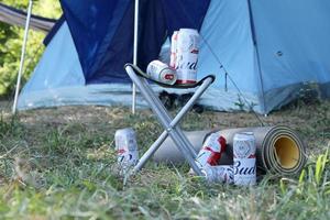 sumy, ukraine - 01 août 2021 quelques canettes de bière alcoolisée budweiser lager sur une chaise de pêcheur à l'extérieur. budweiser est une marque d'anheuser-busch inbev photo