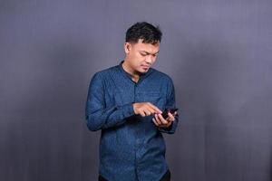 heureux homme asiatique tapant des sms sur fond gris. isolé, concept d'entreprise photo