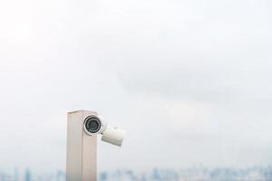 caméra de vidéosurveillance moderne sur fond de ville et de ciel. concept de surveillance, d'enregistrement vidéo et de surveillance photo