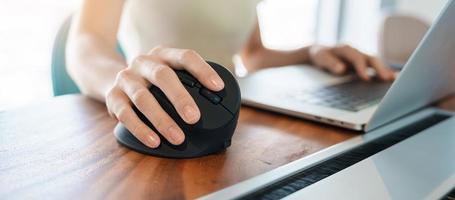 main de femme à l'aide d'une souris ergonomique d'ordinateur, prévention des douleurs au poignet car travail de longue durée. ténosynovite de quervain s, symptôme d'intersection, syndrome du canal carpien ou concept de syndrome de bureau photo