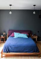 sommier, chambre avec tapis au sol, pot en argile au fond, crédence en bois et miroir. photo
