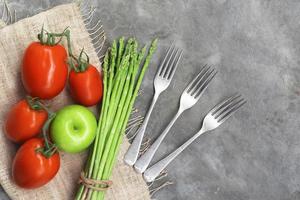 légume alimentaire sain sur fond de pierre a une vue de dessus de fourchette de pomme tomate asperge. photo