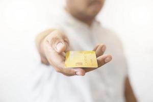 main en gros plan d'un homme asiatique tenant une carte de crédit en or jaune dans sa main. isolé sur fond blanc. concept de finance, commerce, communication, social, technologie, entreprise photo