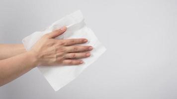 le modèle masculin se sèche soigneusement les mains avec du papier de soie sur fond blanc. photo