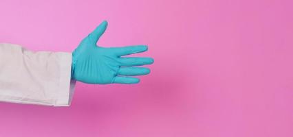 main vide les mains du médecin portent un gant en latex bleu sur fond rose. il porte une robe à manches longues. photo