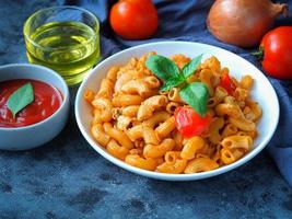 pâtes macaronis à la sauce tomate dans une assiette blanche sur une table de couleur grise photo