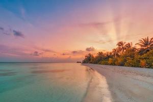 île palmier mer plage de sable. paysage de plage au coucher du soleil. inspirer l'horizon du paysage marin de la plage tropicale. rayons de lever de soleil colorés ciel beau calme tranquille se détendre côte tropicale d'été. vacances voyage vacances photo