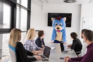 patron habillé en ours s'amusant avec des gens d'affaires dans un bureau branché photo