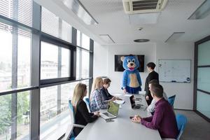 patron habillé en ours s'amusant avec des gens d'affaires dans un bureau branché photo