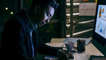 un jeune homme d'affaires se concentrant sur une analyse de projets de travail dans son bureau jusque tard dans la nuit. photo