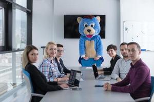 patron habillé en ours s'amusant avec des gens d'affaires dans un bureau branché photo