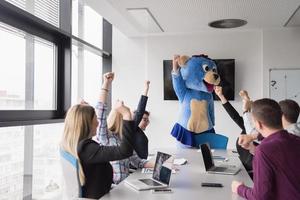 patron habillé en ours s'amusant avec des gens d'affaires dans un bureau branché photo