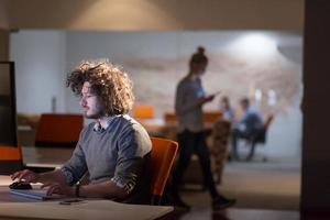 homme travaillant sur ordinateur dans un bureau sombre photo