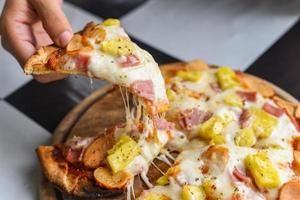 la pizza maison italienne est cuite de la nourriture traditionnelle - une tranche de fromage à pizza sur un plateau en bois et servie sur une table en bois photo